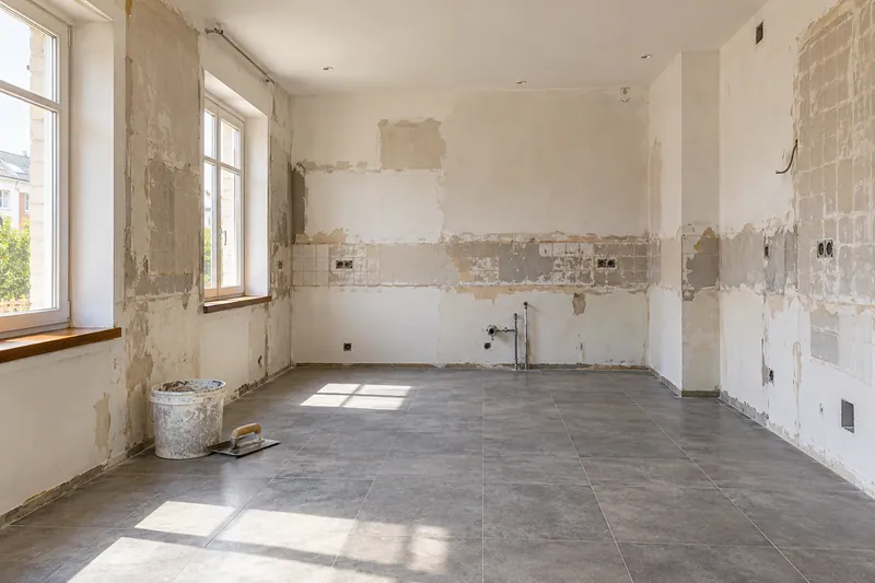 Visualización conceptual IA: Cocina sin muebles con paredes en preparación y zonas de enlucido.